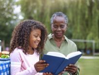 girl and older woman reading a book