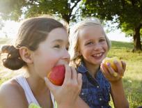 two happy girls eating apples