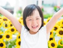 child smiling in a sunflower field