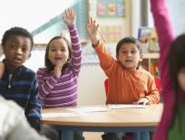 Children in class with their hands in the air