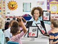 Teacher with young students showing the alphabet