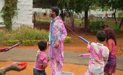 children spraying man with water and colours