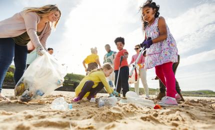 children and adults collecting rubbish on a beach