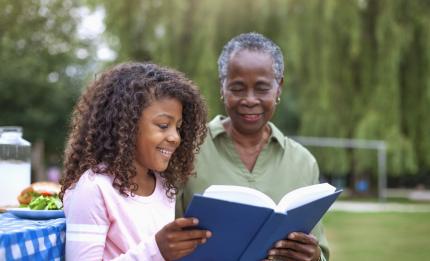 girl and older woman reading a book