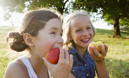 two happy girls eating apples