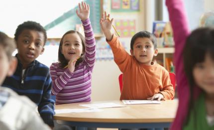 Children in class with their hands in the air