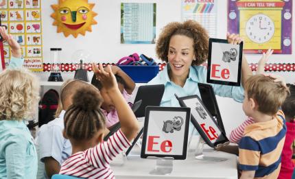 Teacher with young students showing the alphabet