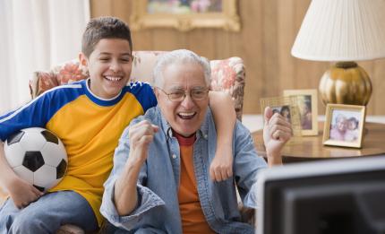 Screenshot: boy and grandfather watching football on TV