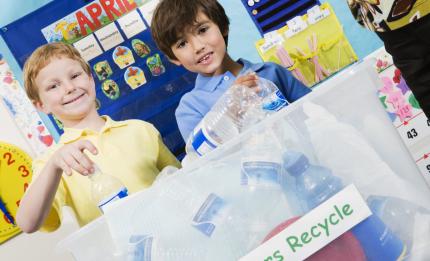 children putting plastic bottles in recycling box