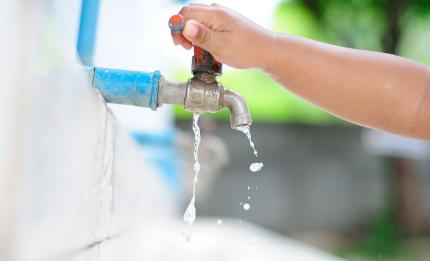 child turning off an outdoor tap