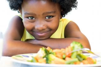 girl looking at plate of vegetables