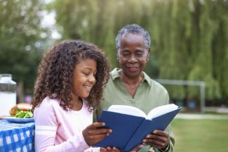 girl and older woman reading a book