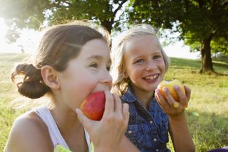 two happy girls eating apples