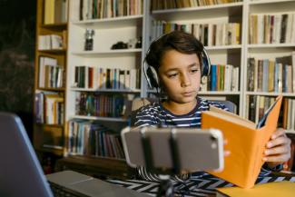 boy studying with a book and headphones