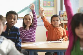 Children in class with their hands in the air