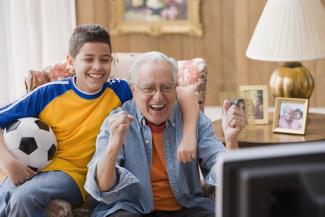 Screenshot: boy and grandfather watching football on TV