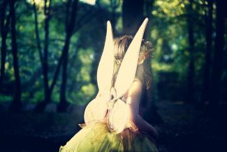 girl wearing fairy wings in forest