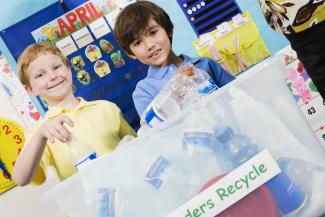 children putting plastic bottles in recycling box