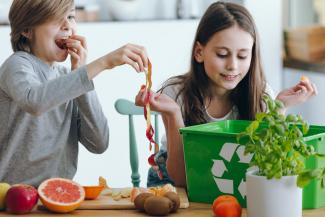 children putting food scraps in compost box