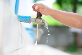 child turning off an outdoor tap